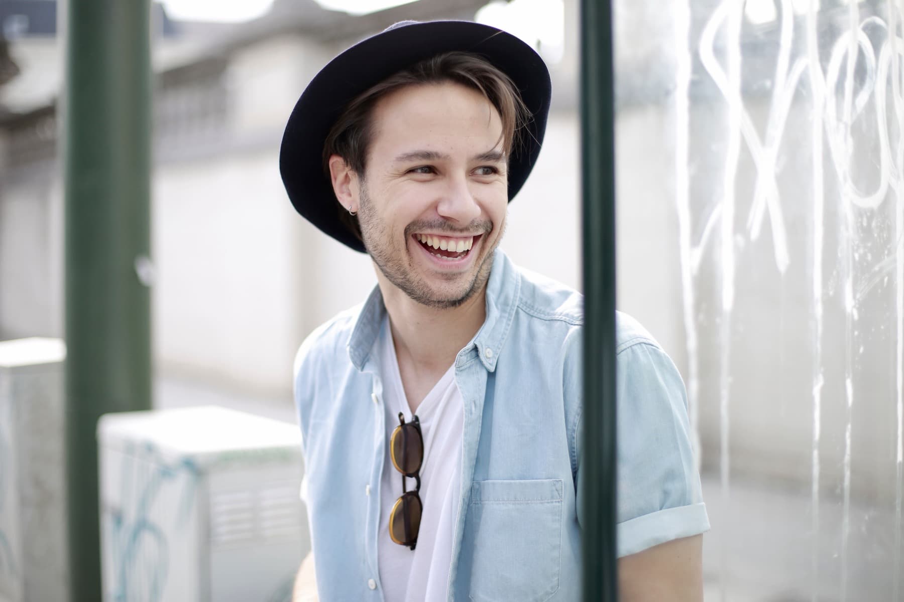 A man in a brimmed hat laughing, his upper teeth showing.