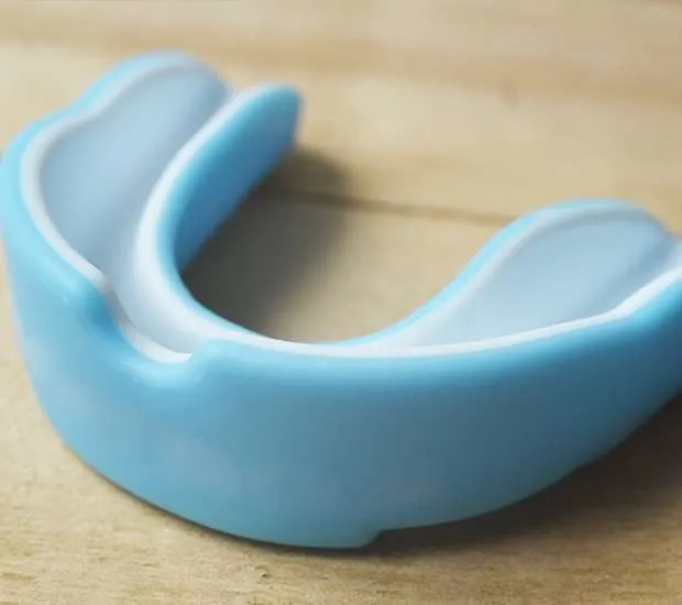 A blue mouth guard resting on a wooden surface.