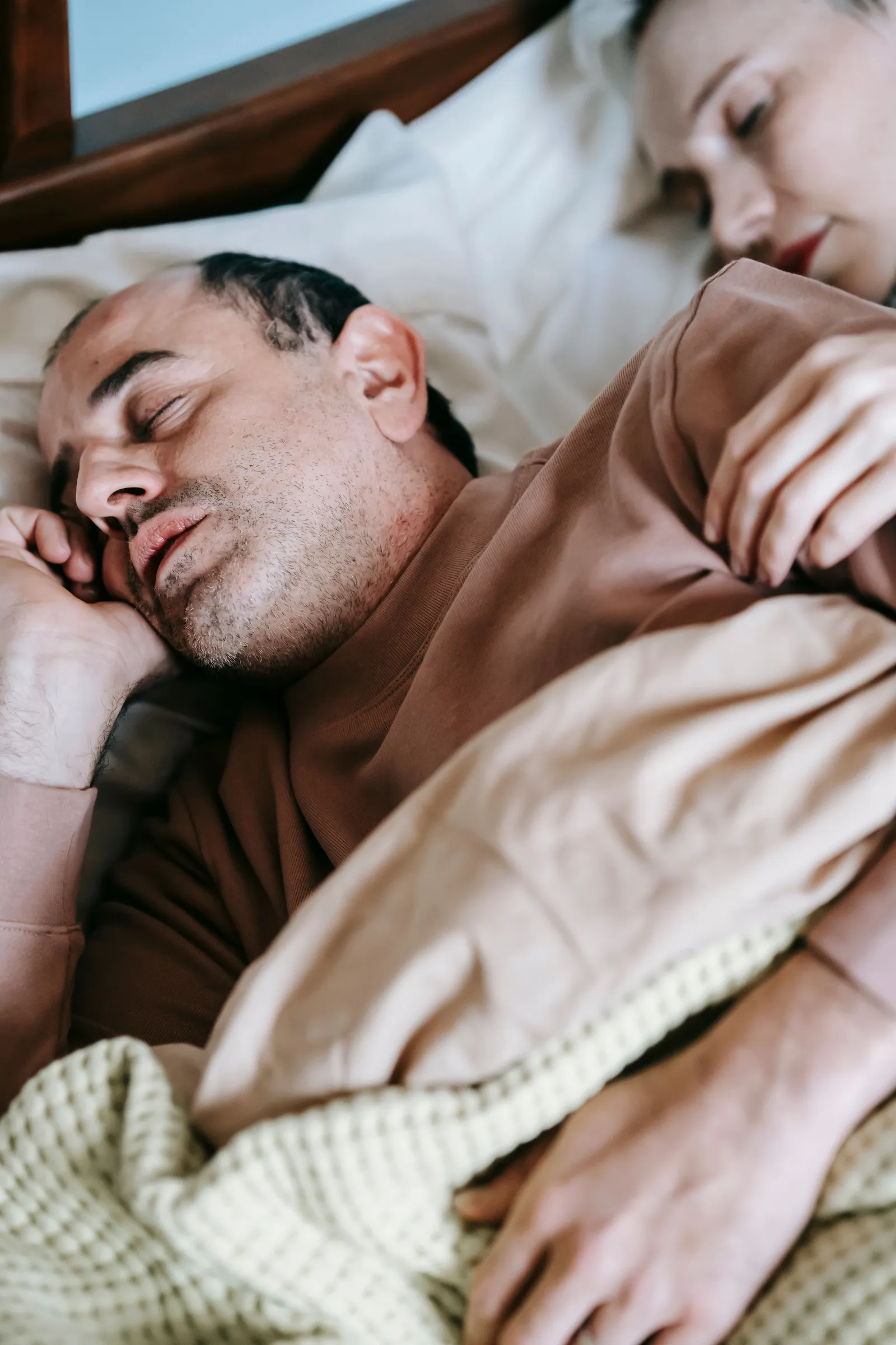 A man asleep on his side under a blanket.