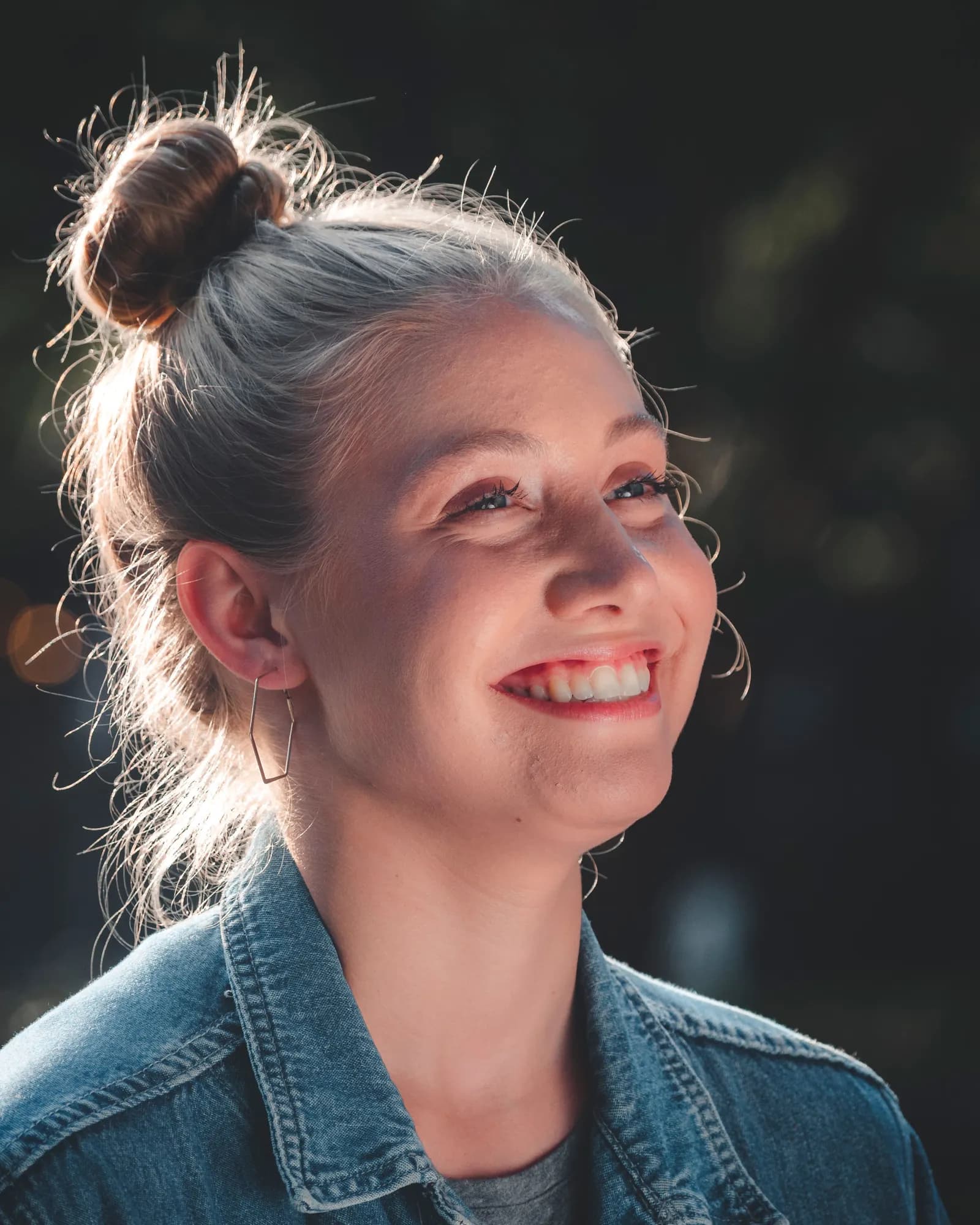 A woman smiling, her head turned up toward the light.