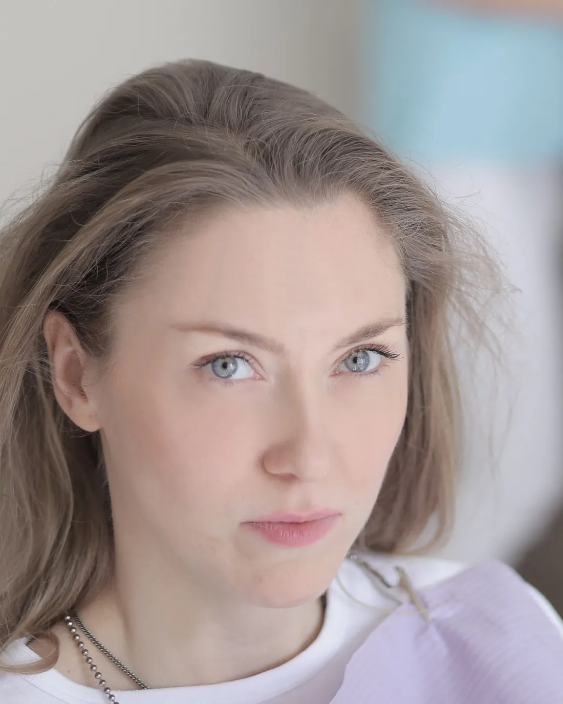 A woman with long light-brown hair in a dental bib, looking toward the camera.