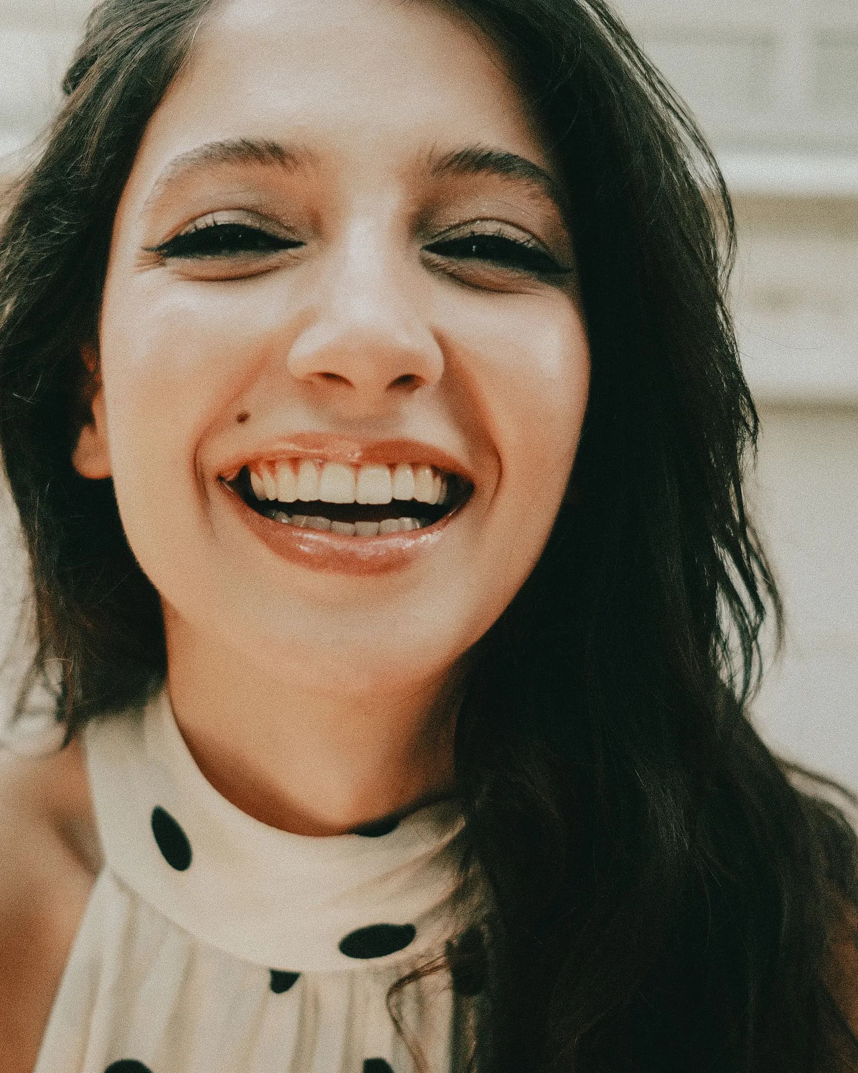 A young woman with long dark hair laughing at the camera.